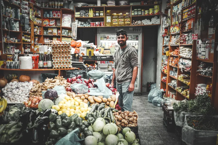 Una bottega di alimentari con il titolare fra le cassette della verdura